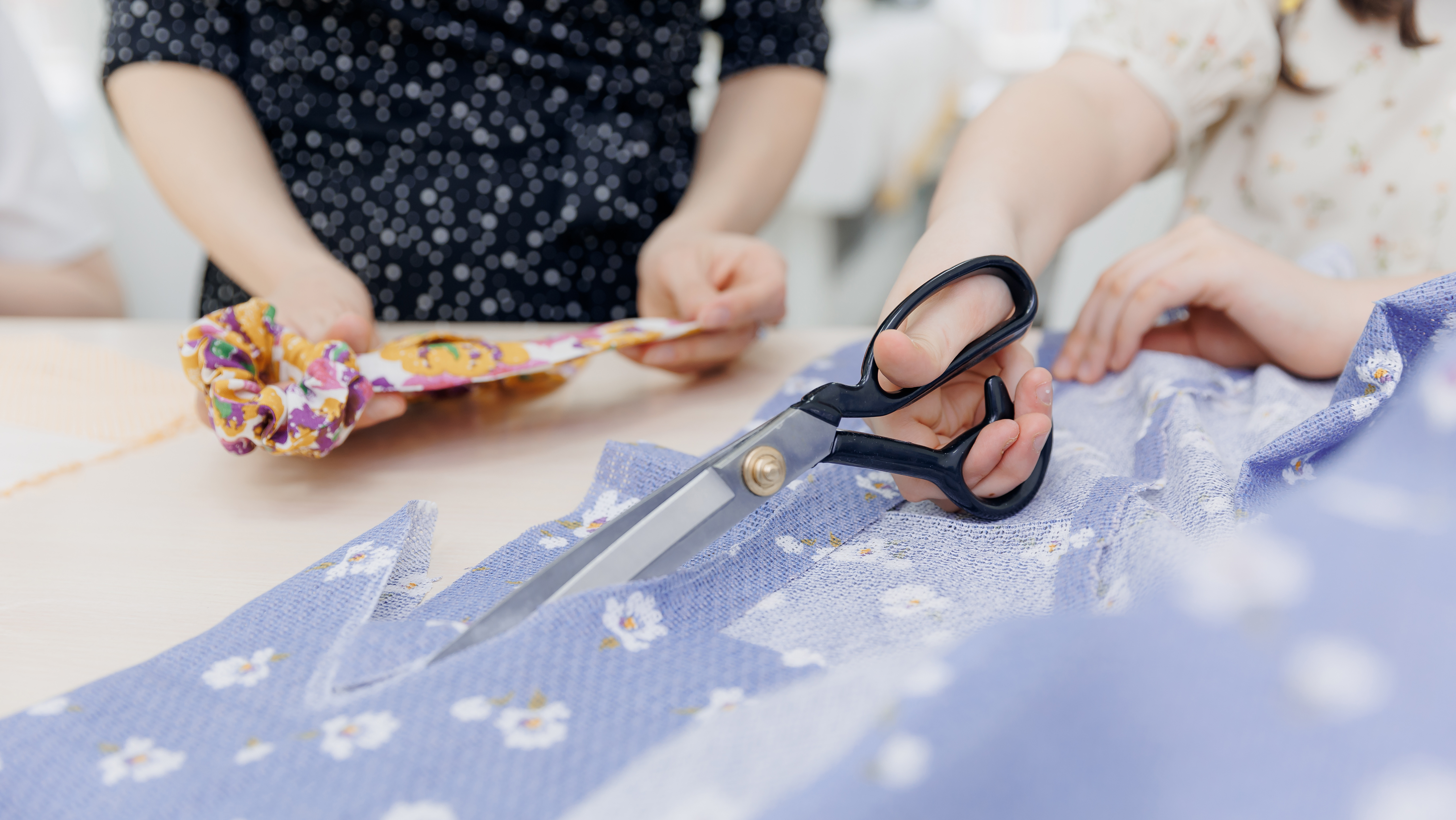 Children crafting with fabrics at a table.